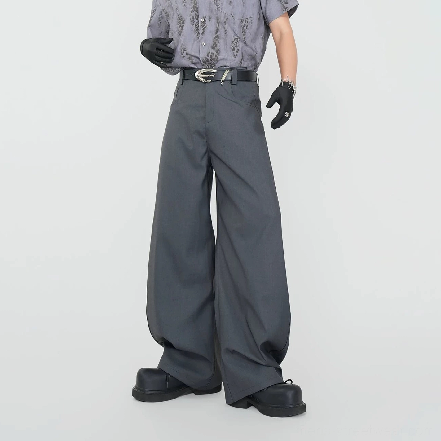 Three-quarter side view of grey wide-leg tailored trousers with silver buckle, clean waistband, smooth suiting texture, and floor-grazing hems