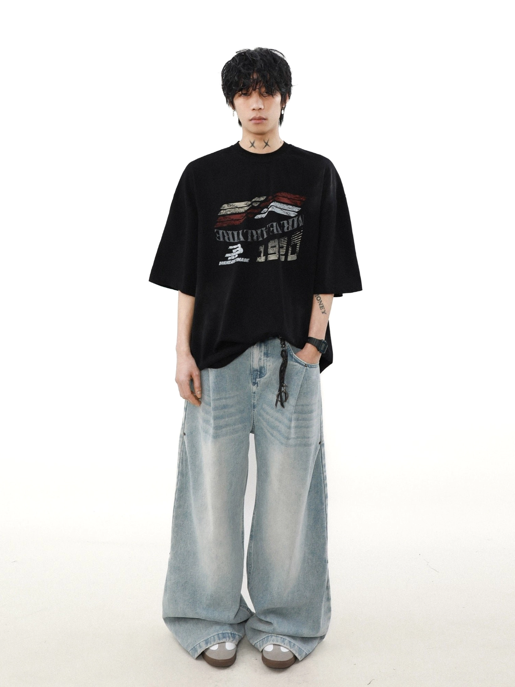 Full-body male model wearing a black oversized racing graphic tee with light-wash baggy jeans in a relaxed streetwear outfit