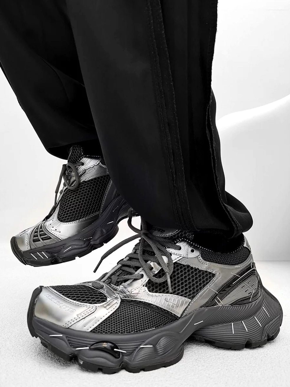 Gunmetal grey and silver chunky sneakers shown on foot with metallic toe box, layered mesh upper, and oversized retro rubber sole