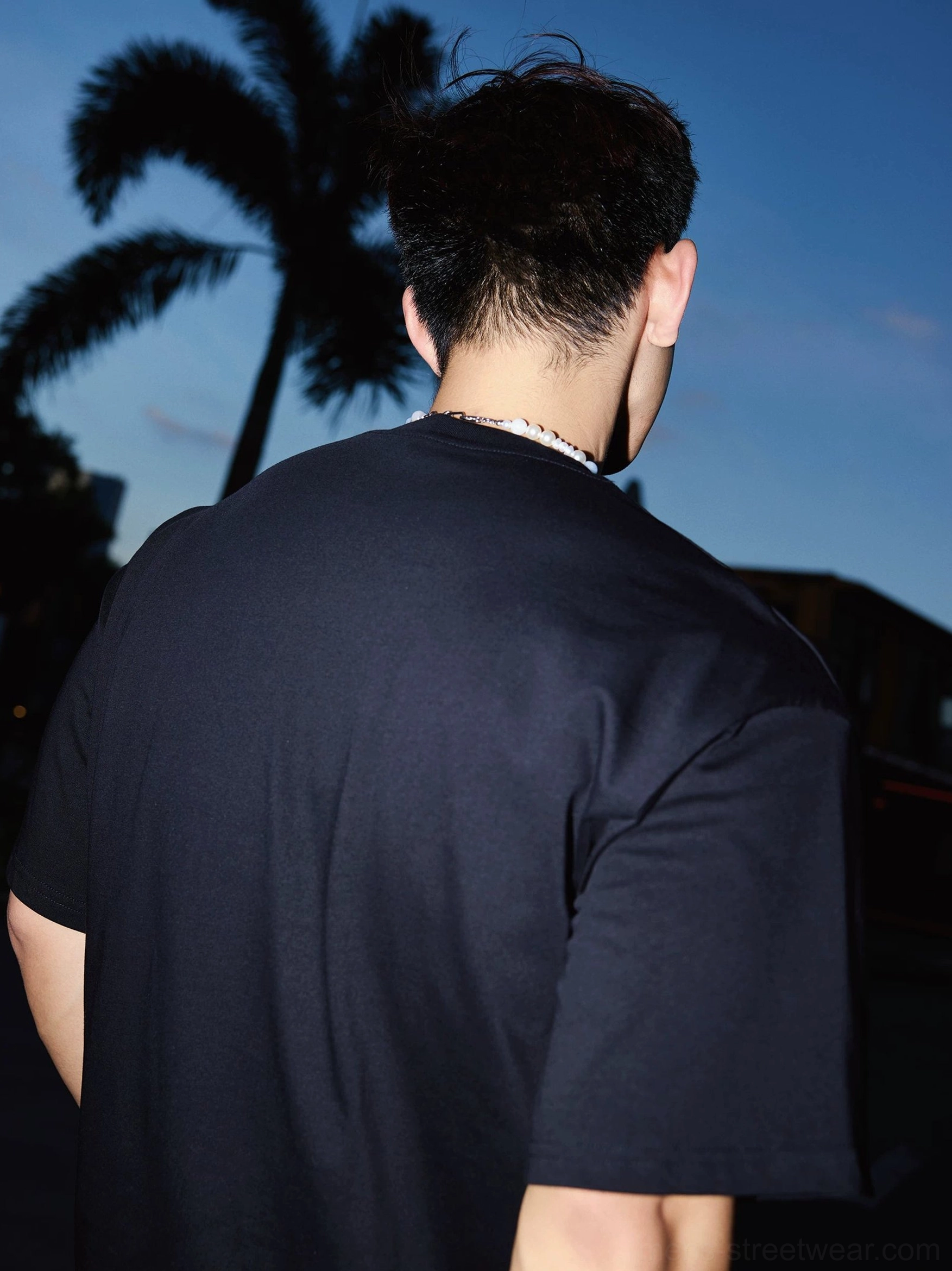 Back view of a relaxed black cotton short sleeve streetwear T-shirt showing the clean solid black rear design and loose boxy fit