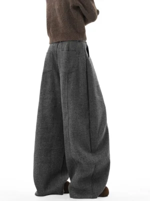 Heather dark gray oversized balloon trousers shown from the rear three-quarter view with patch pockets, tailored seam lines, and voluminous wide legs