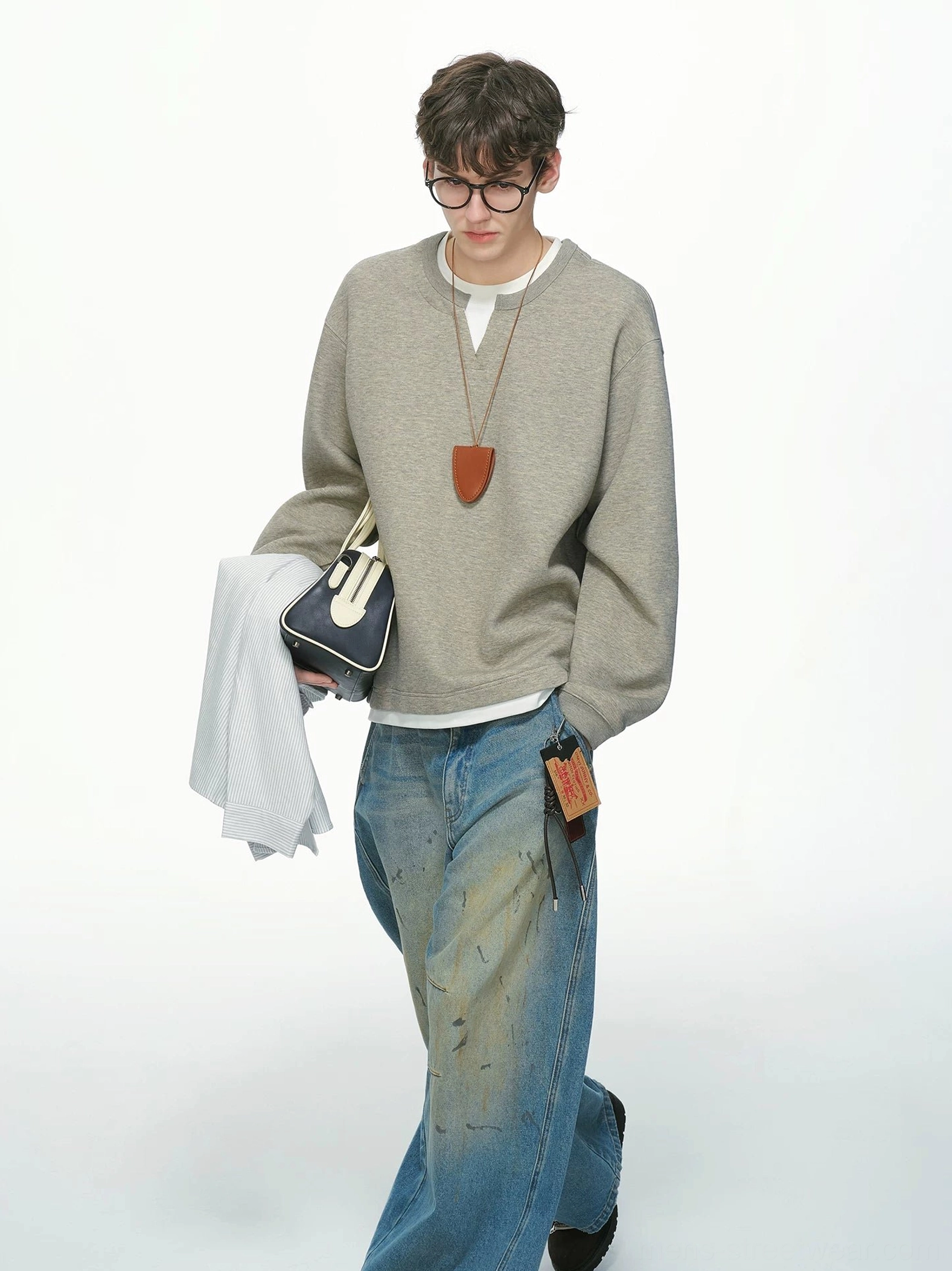 Heather gray men's Korean streetwear sweatshirt shown while walking with a relaxed loose silhouette, wide-leg jeans, clutch, and pendant necklace