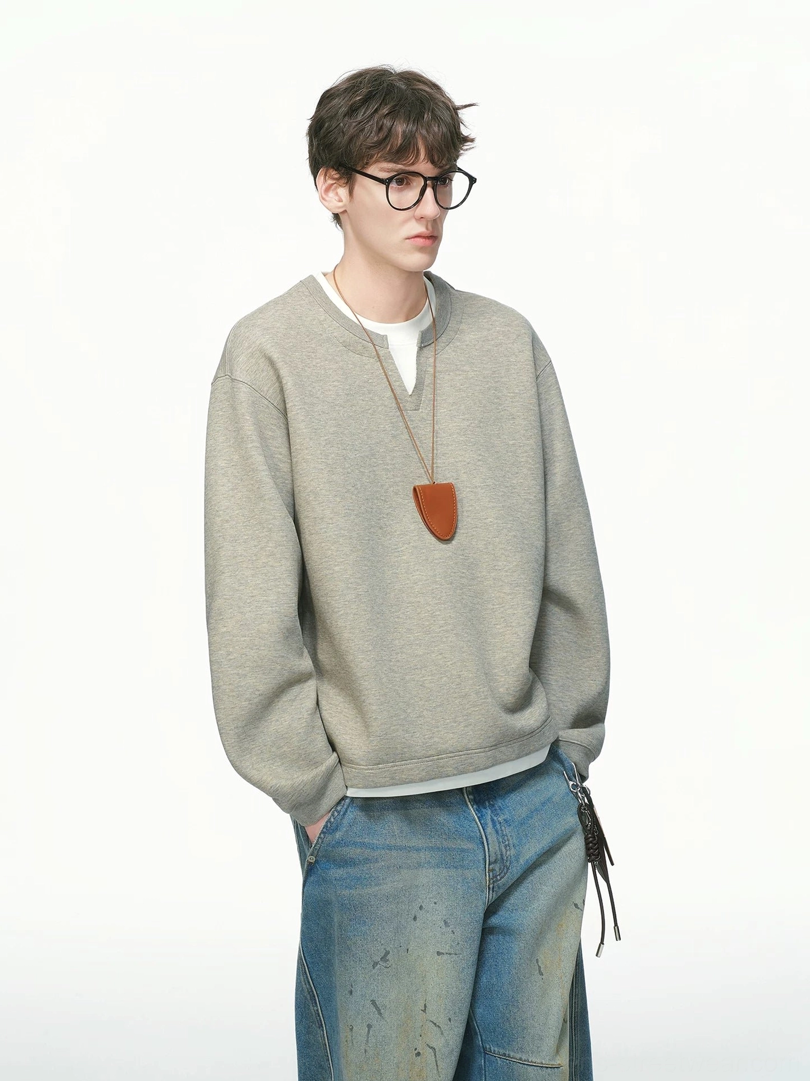 Heather gray men's layered crew neck sweatshirt in a front three-quarter studio view with white layered trim, wide-leg denim, and leather pendant styling