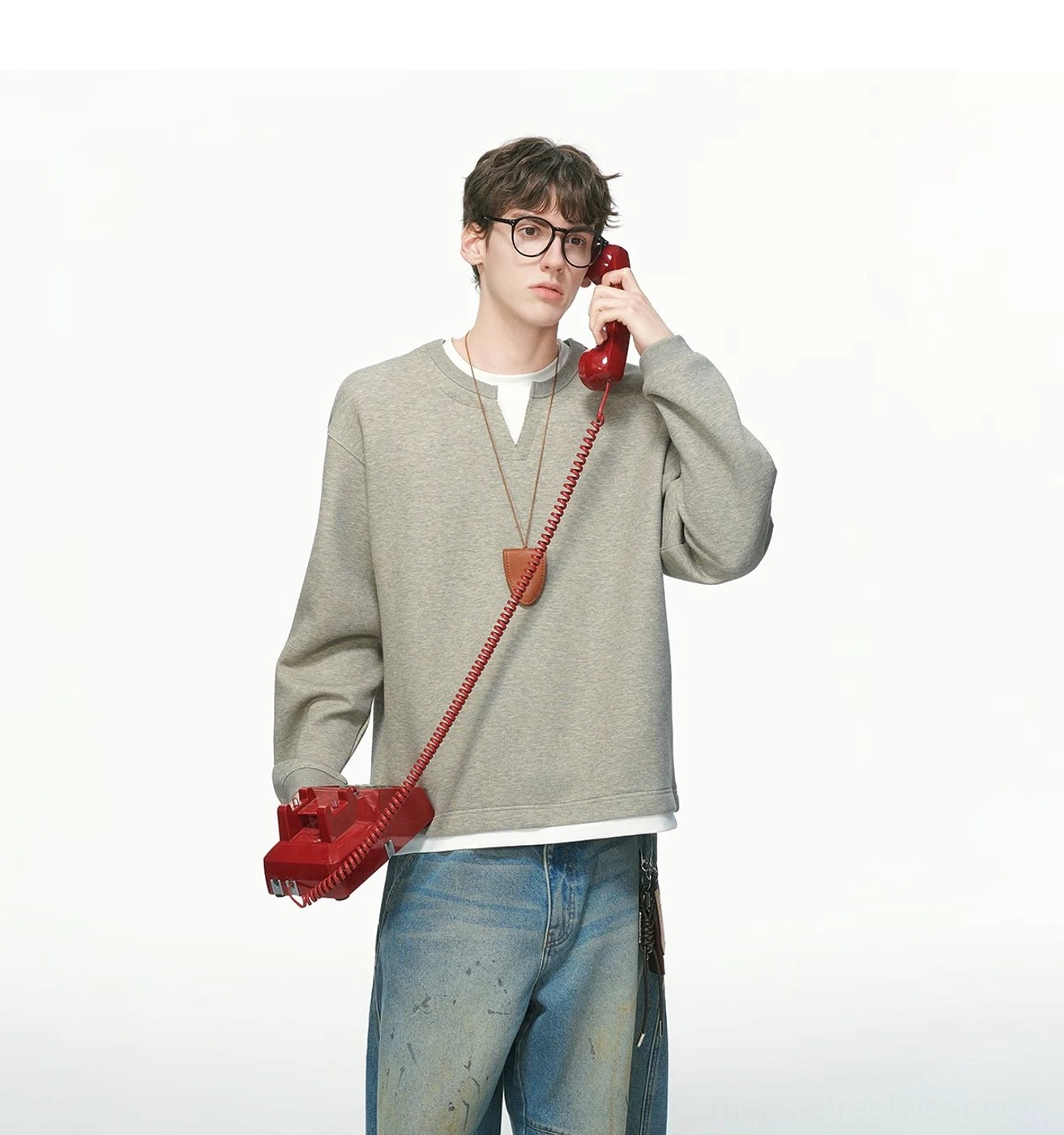 Front three-quarter view of a heather gray men's layered sweatshirt with white trim, wide-leg jeans, leather pendant, and retro casual styling