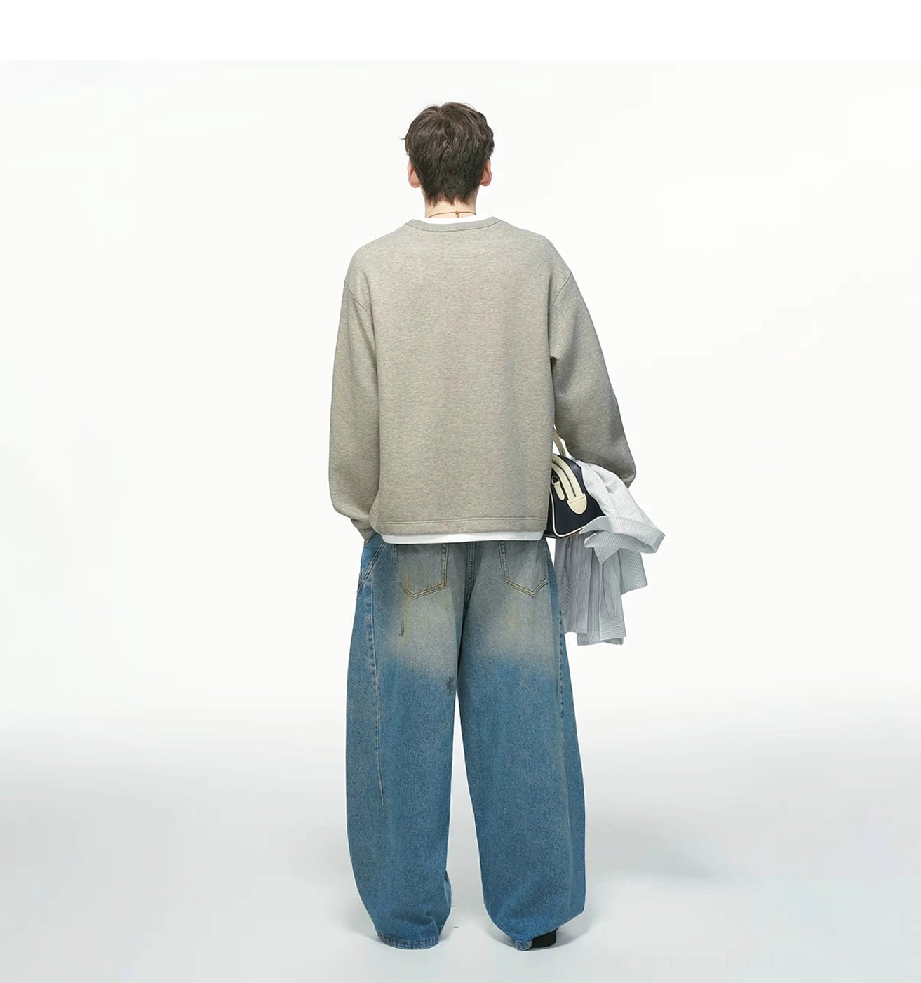 Back view of a heather gray men's oversized layered sweatshirt with clean plain back, straight hem, white layered trim, and wide-leg jeans