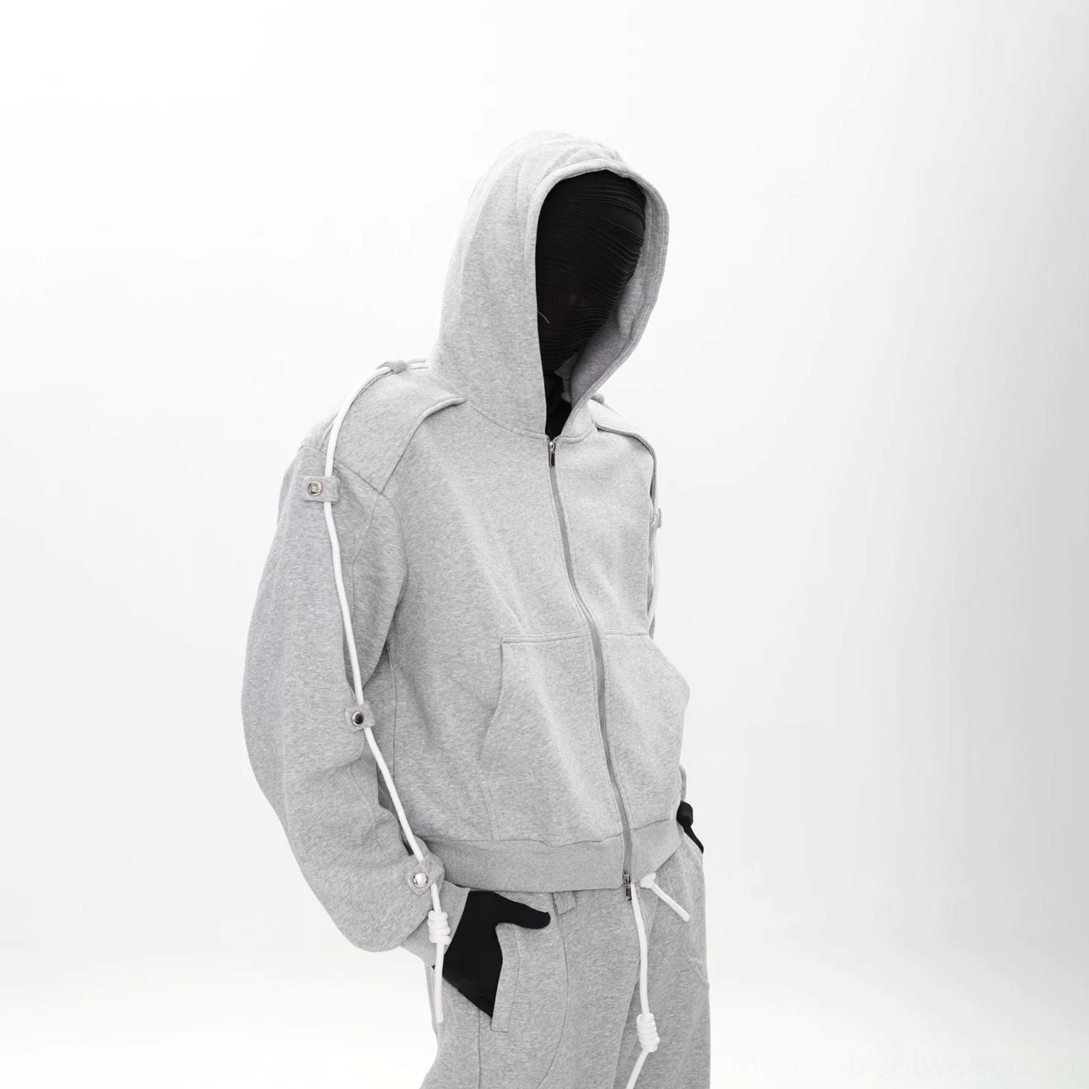 Three-quarter view of heather gray modular tracksuit with buttoned shoulder tabs, adjustable sleeve cords, and wide-leg pants