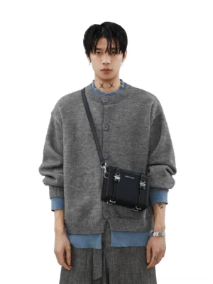 Full body view of men's gray oversized button knit cardigan with wide leg trousers and brown slip on shoes
