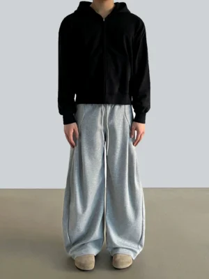 Heather gray pleated wide-leg lounge pants with elastic drawstring waist styled with a black zip-up hoodie front view
