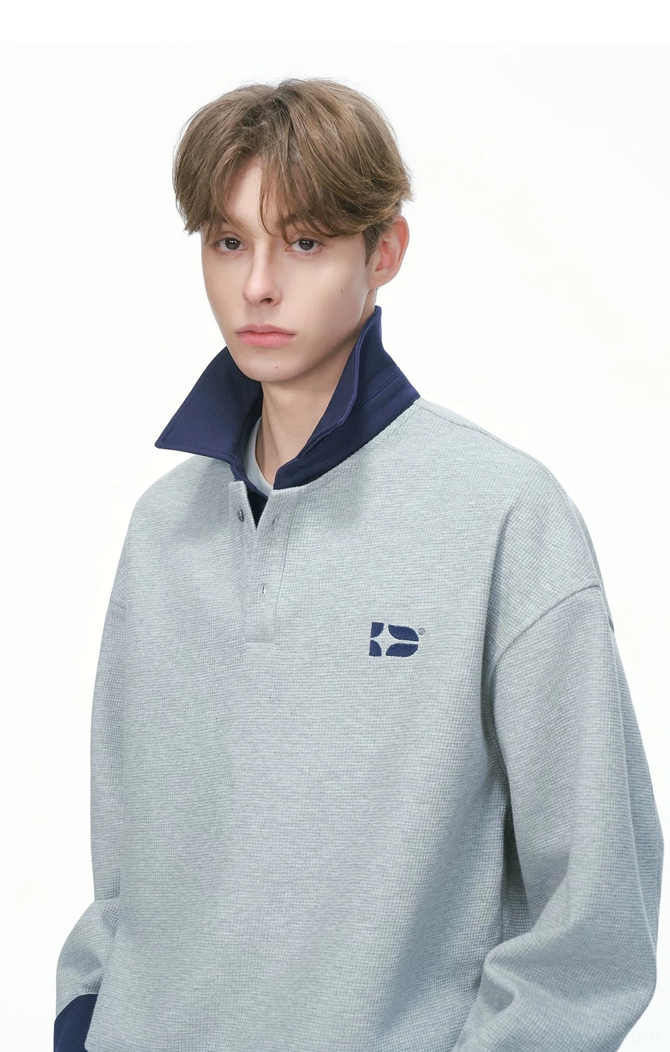 Close-up of heather gray rugby sweatshirt collar with quarter-button placket textured knit fabric and embroidered chest logo