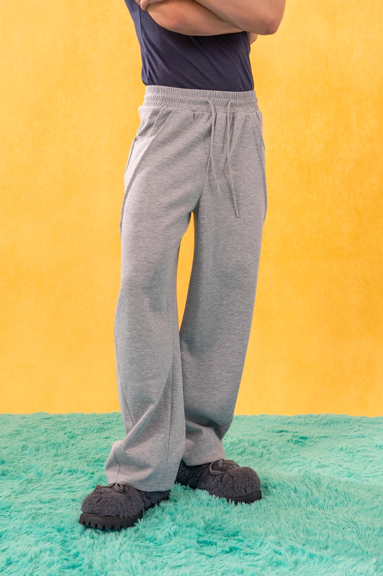 Side view of heather gray slanted spliced wide-leg sweatpants with curved seam and loose flowing leg silhouette