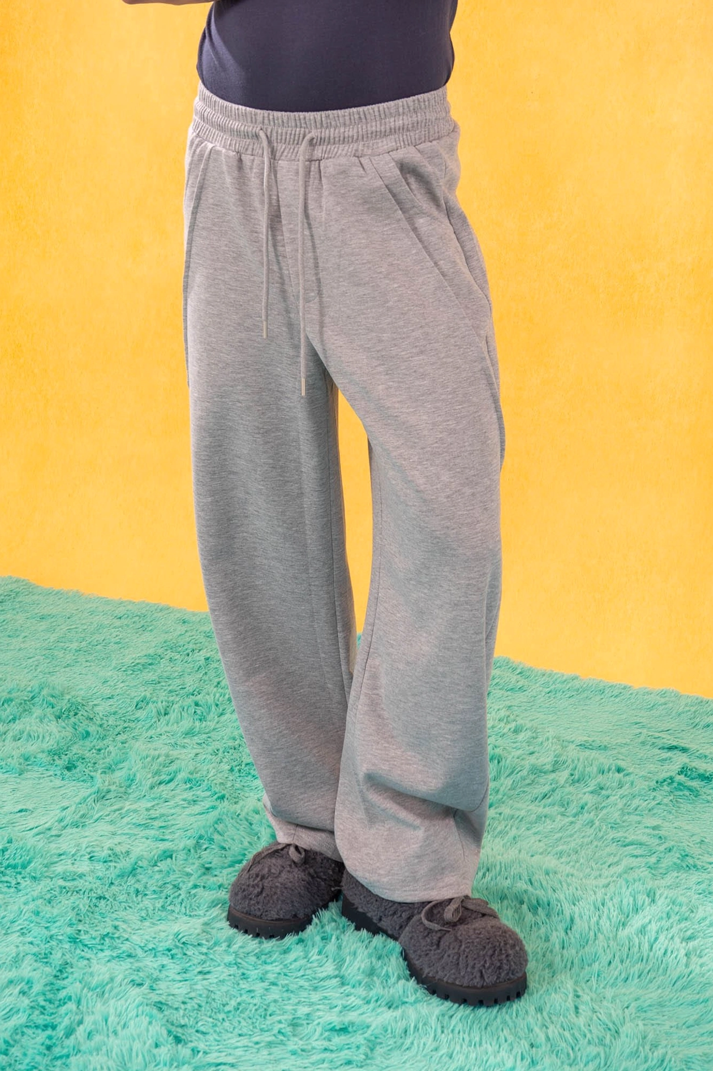Close-up of heather gray slanted spliced wide-leg sweatpants showing drawstring waist and soft draping fabric