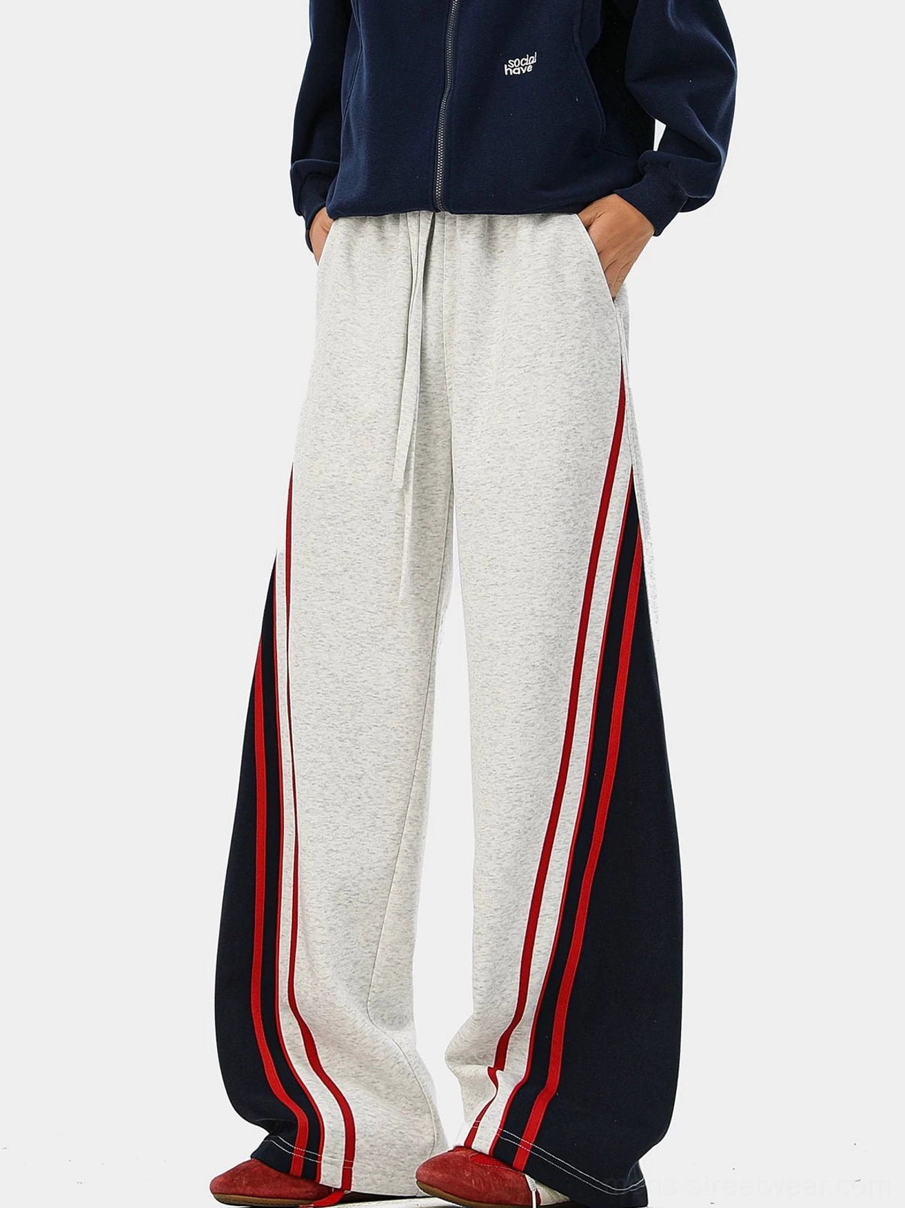 Heather gray wide-leg varsity track pants with red and navy contrast side panels, shown with a navy zip-up hoodie