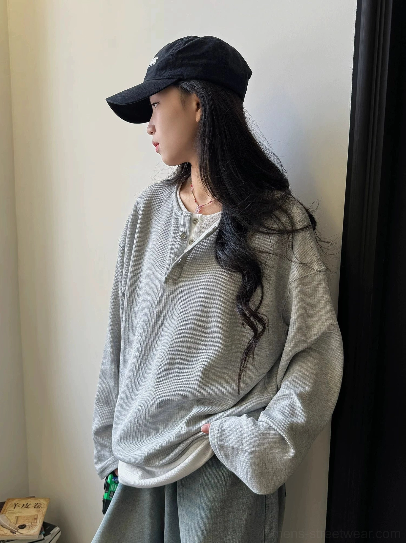 Close side view of a female model wearing a heather gray waffle knit Henley shirt with loose long sleeves
