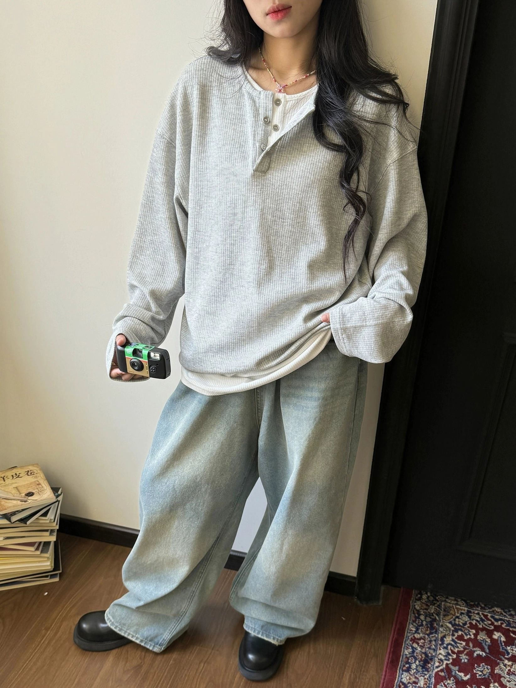 Female model wearing a heather gray waffle knit Henley long-sleeve shirt with washed wide-leg jeans and layered styling