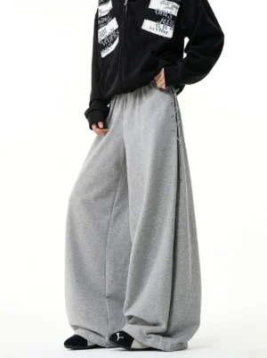 Heather gray wide-leg sweatpants with metal eyelet side lacing and oversized silhouette styled with a black graphic hoodie