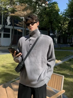 Heather grey half-button turtleneck sweater with relaxed loose fit and ribbed knit texture worn with a crossbody bag