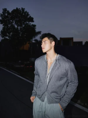 Heather grey men's knit button cardigan shown from a three-quarter front angle on a city street, featuring a relaxed streetwear fit and fine textured knit fabric