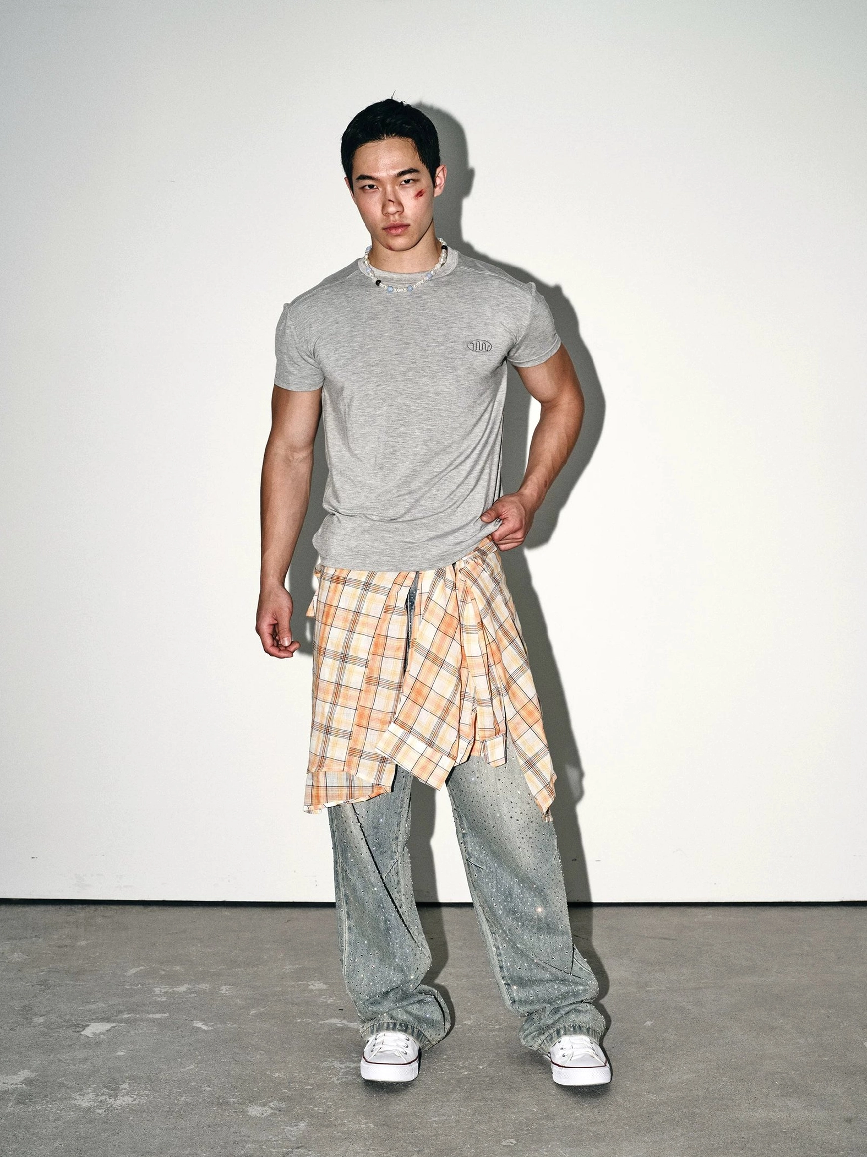 Front view of heather grey minimal embroidered slim fit crew neck streetwear tee with plaid shirt tied at waist