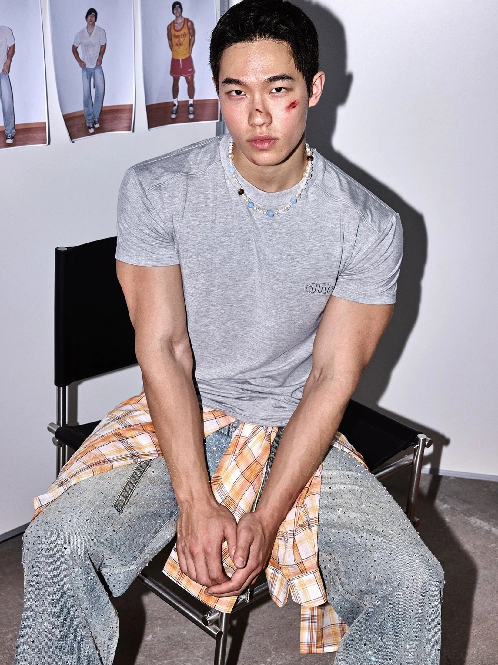 Three-quarter seated view of heather grey fitted streetwear tee with subtle embroidered chest detail