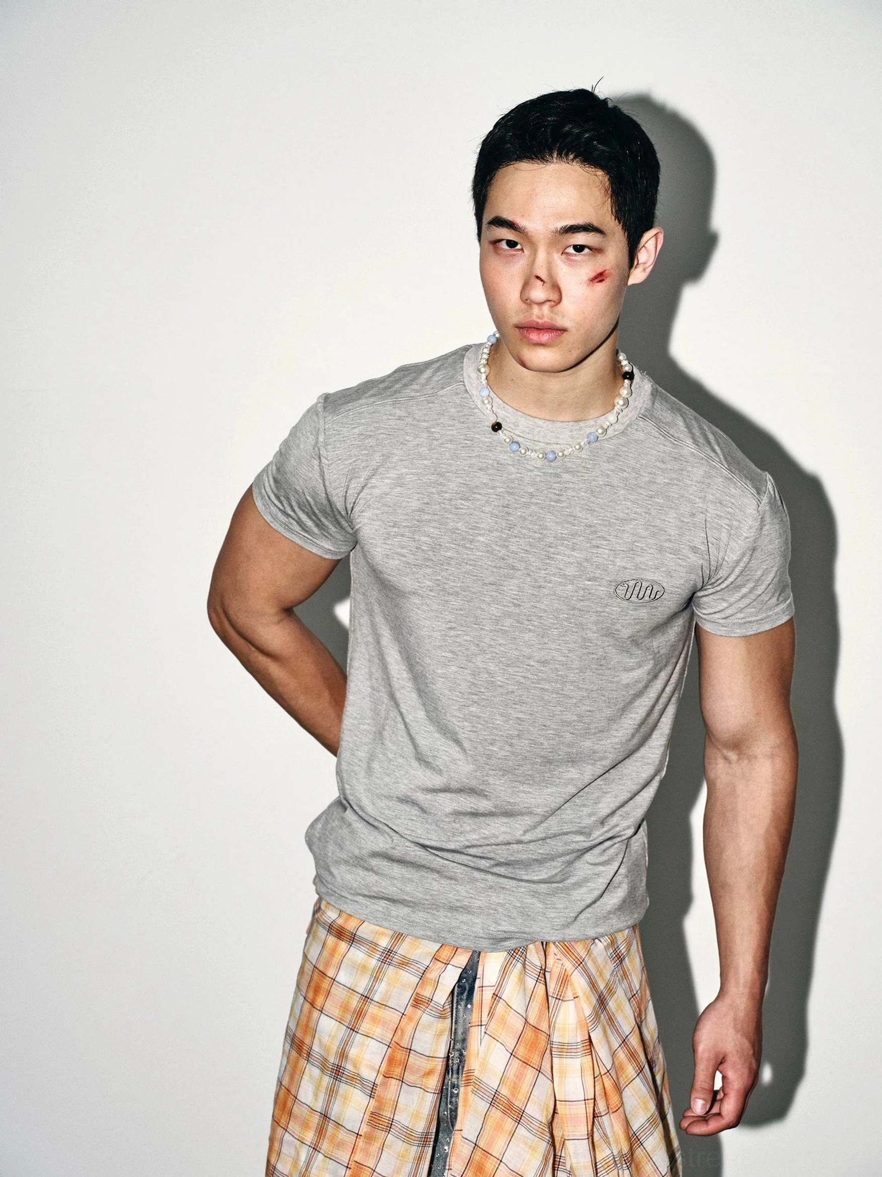 Three-quarter side view of male model wearing heather grey minimal logo slim fit streetwear tee