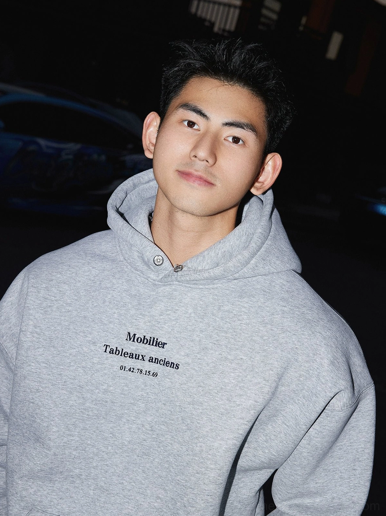 Close-up of heather grey hoodie chest featuring Mobiler Tableaux anciens text graphic and relaxed hood detail