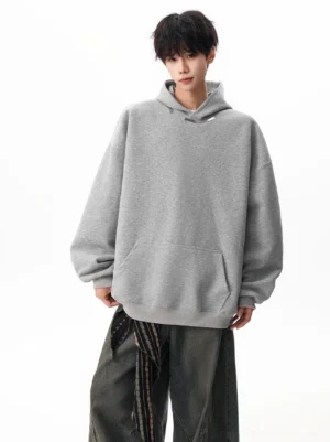 Heather grey oversized drop shoulder hoodie with relaxed fit, lined hood, and kangaroo pocket styled with wide-leg trousers