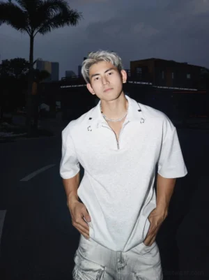 Heather grey oversized quarter-zip polo shirt with short sleeves and metal collar details styled in a nighttime urban streetwear setting