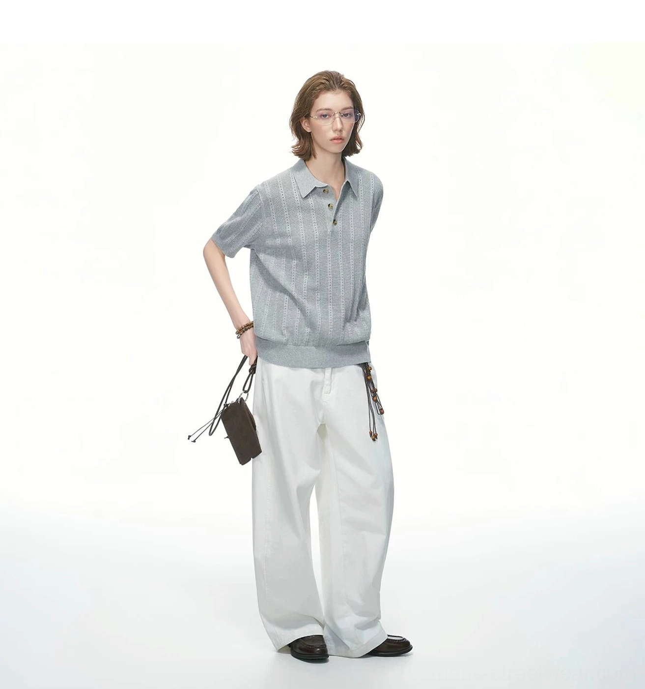 Side-back view of heather grey pointelle knit polo shirt with loose silhouette styled with white wide-leg pants and handbag