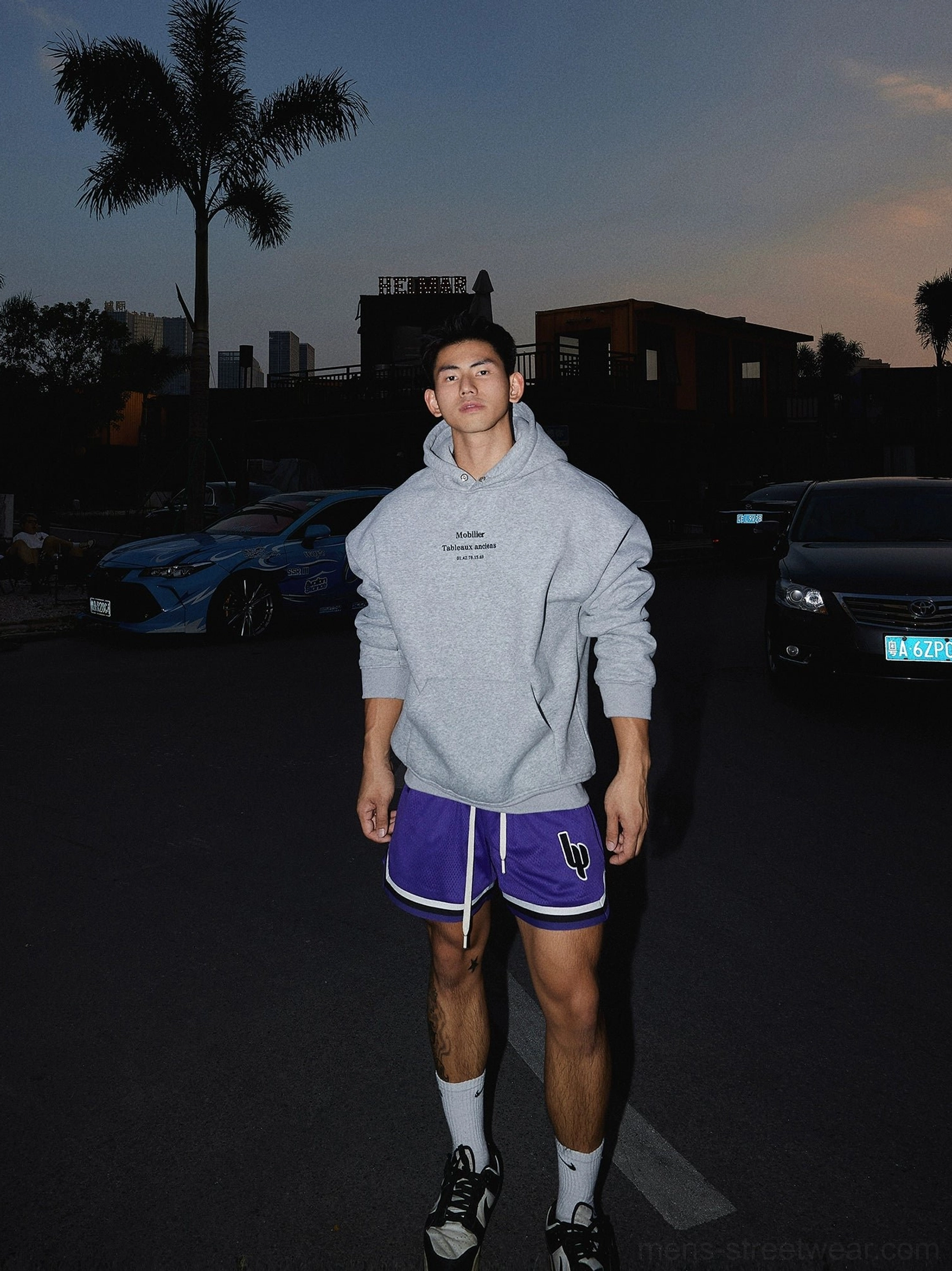 Heather grey relaxed text graphic hoodie paired with purple athletic shorts and black sneakers in urban streetwear styling