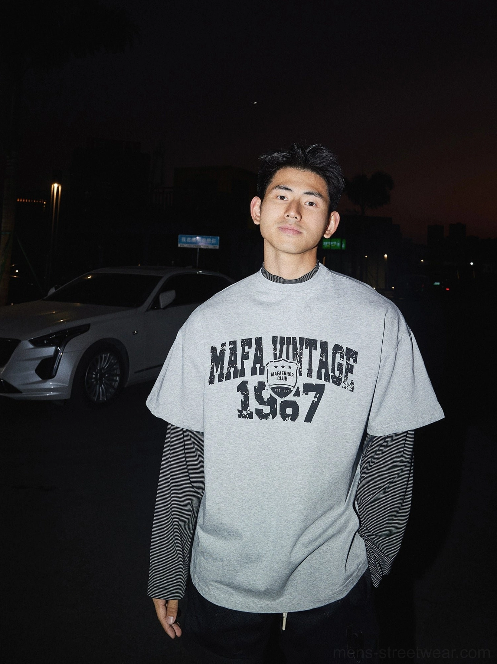 Heather grey oversized vintage graphic layered tee with distressed varsity print and attached contrast sleeves styled on a male streetwear model
