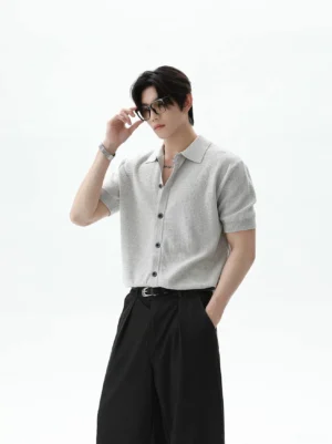 Heather light gray short sleeve polo knit cardigan styled with black wide leg trousers in a minimalist studio