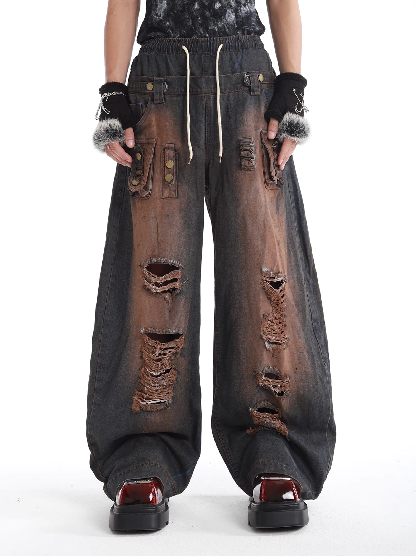 Close front view of heavily distressed wide-leg denim pants with faded wash flap cargo pockets and streetwear styling
