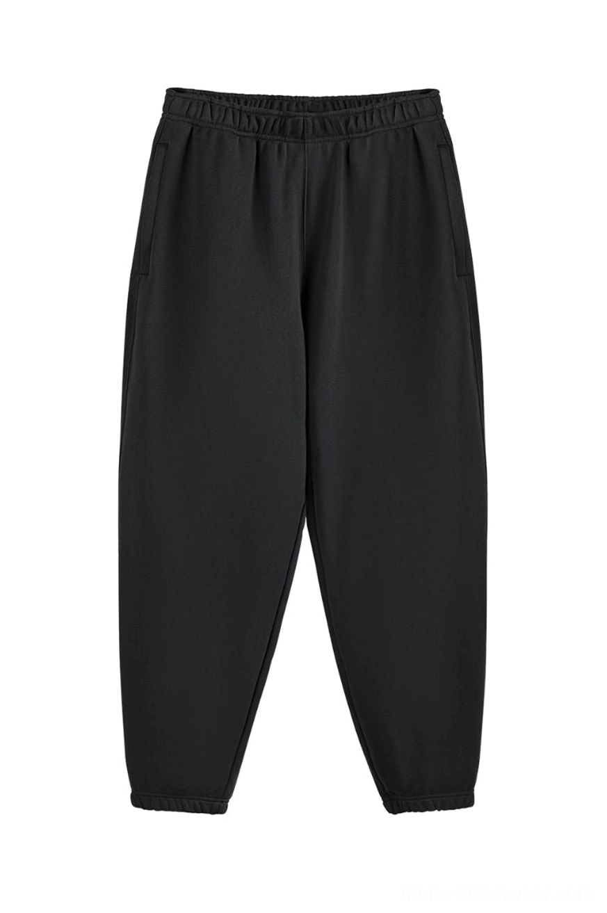 Black heavyweight oversized cotton sweatpants with elastic waistband tapered cuffs and side pockets front flat lay