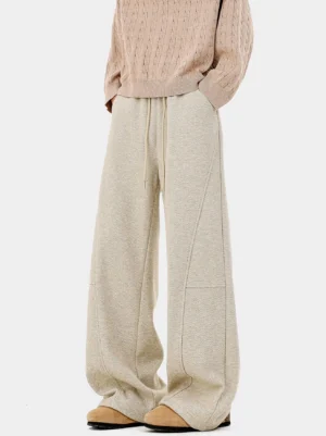 Cream beige herringbone wide-leg trousers with drawstring waist styled with a pink cable-knit sweater and loafers