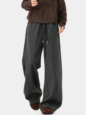 Dark charcoal gray herringbone wide-leg trousers styled with a brown cable-knit sweater and suede sandals in a relaxed Korean streetwear outfit