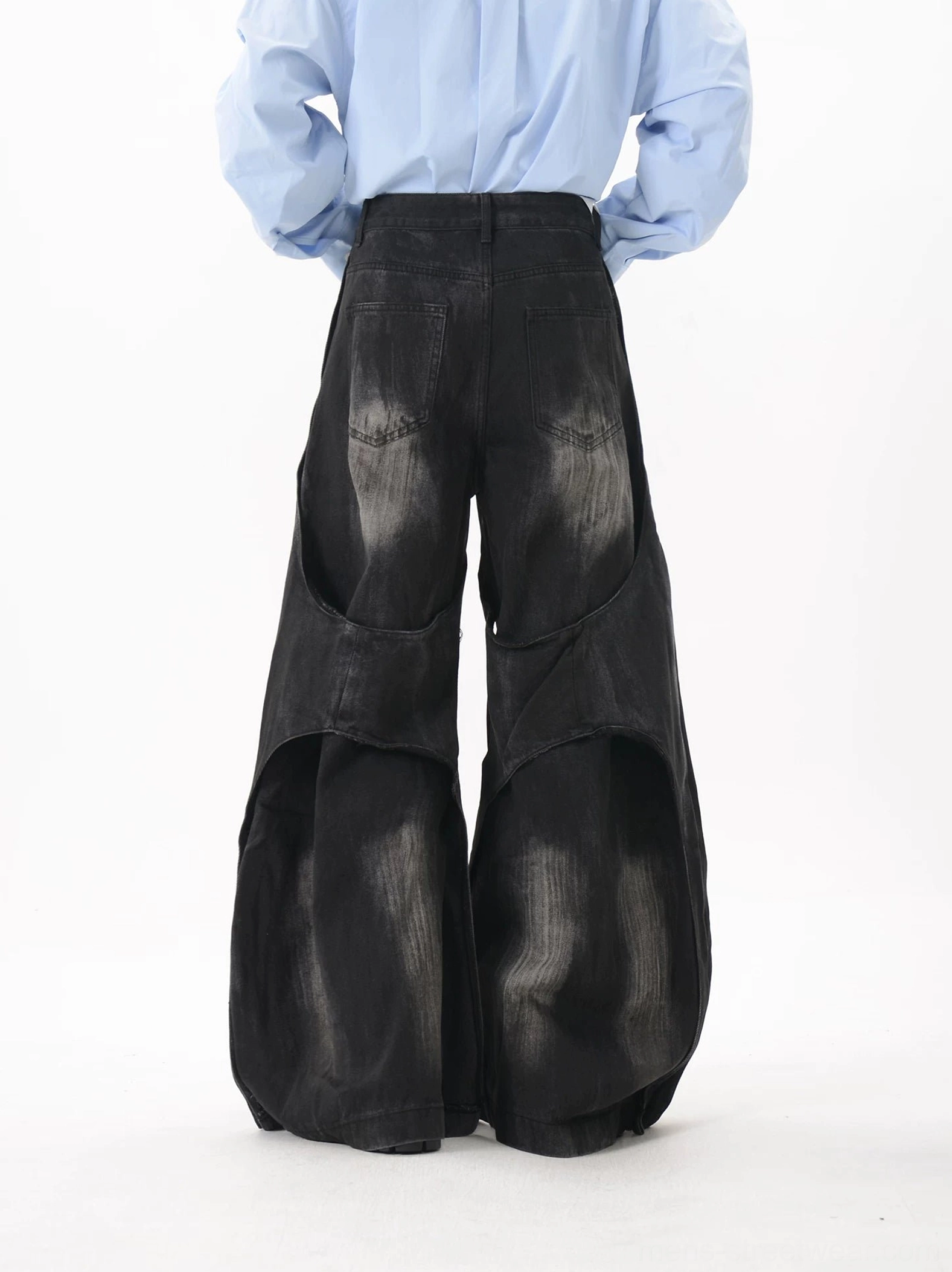 Rear view of high-waisted deconstructed wide-leg jeans showing classic back pockets, patchwork distressed denim, and oversized black silhouette