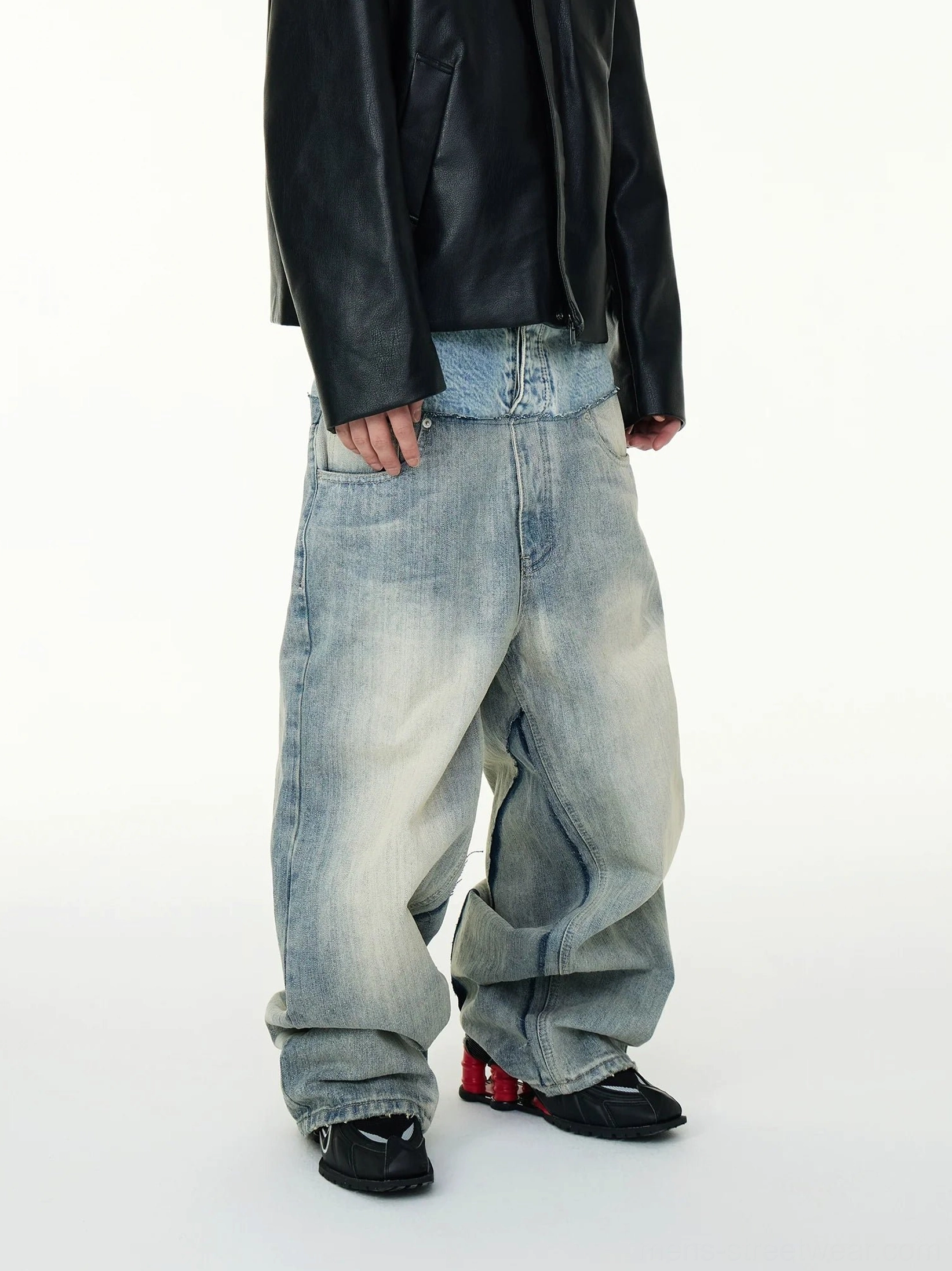 Angled front view of high waisted two tone baggy jeans with layered waistband faded denim texture and relaxed streetwear silhouette
