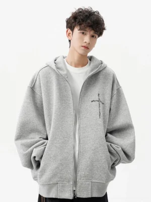 Heather gray oversized zip-up hoodie shown from the front with pointed horn hood, contrasting cross embroidery, drop shoulder design, and relaxed Korean streetwear silhouette