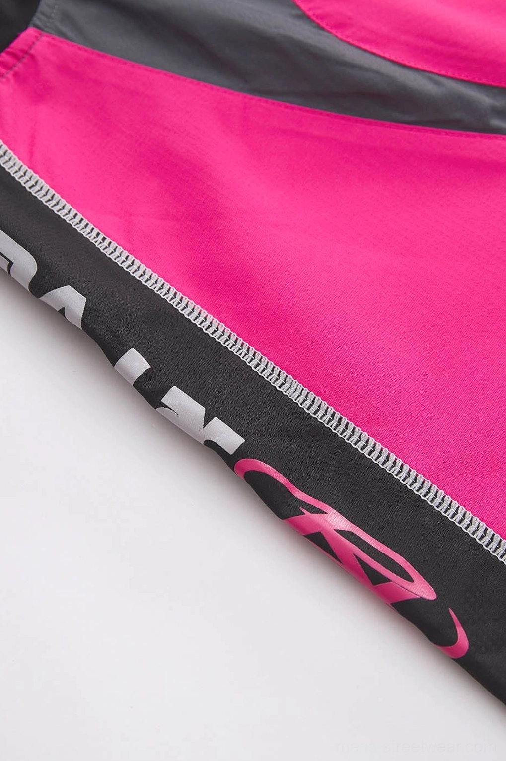 Close-up fabric detail of hot pink racing jersey with black trim white piping and contrast side tape