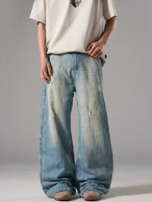 Front full-body view of ice blue distressed wide-leg jeans with diamond-shaped rips and a long relaxed streetwear silhouette