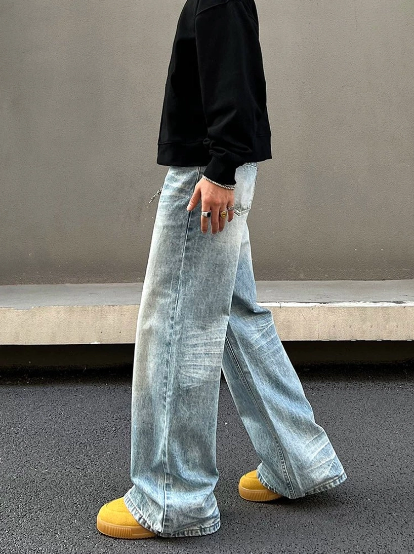 Side rear view of vintage faded light blue wide straight jeans with loose full-length legs and raw-style hem detail