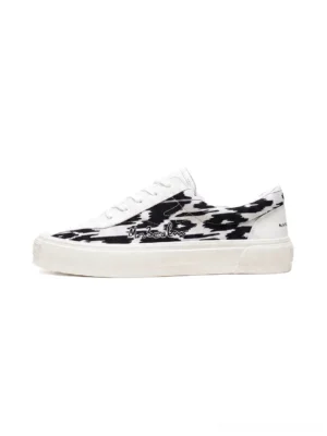 Left side profile of white and black ikat graphic low-top skate shoes with embroidered detail and clean white rubber sole