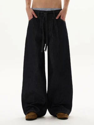 Front view of dark indigo balloon jeans with ultra-wide legs, drawstring waist, oversized Korean streetwear silhouette, and puddled hems