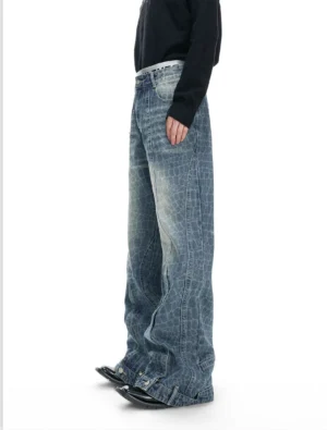 Side profile of indigo crocodile-pattern wide-leg jeans with a high waist, belt loops, tailored side panels, vintage denim wash, black knit top, and leather dress shoes