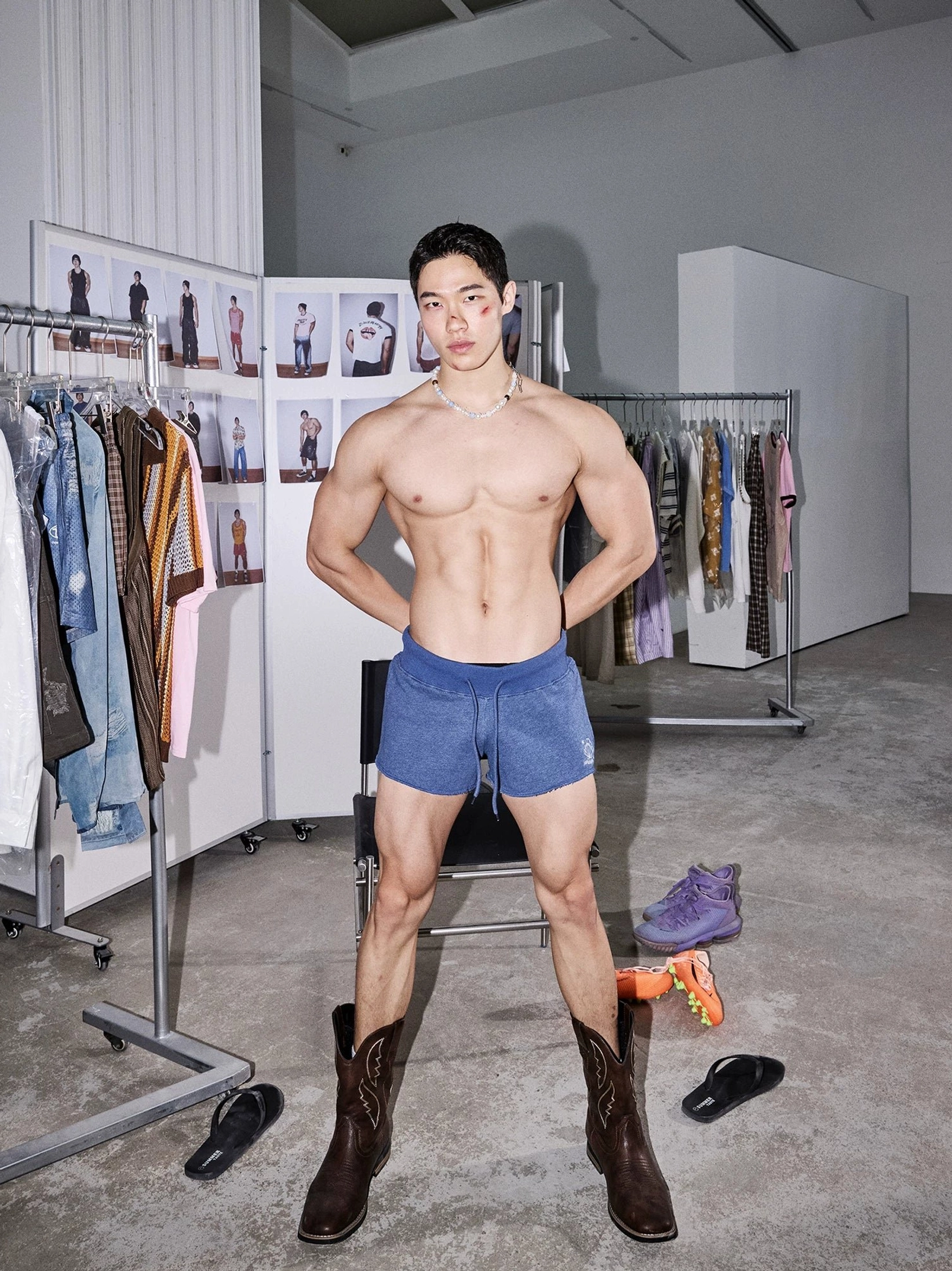 Seated model wearing medium-dark indigo cutoff lounge sweat shorts in a contemporary clothing studio