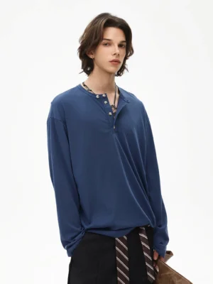 Deep indigo Henley long sleeve tee with four-button placket styled with black pants and a striped tie in modern Seoul street style