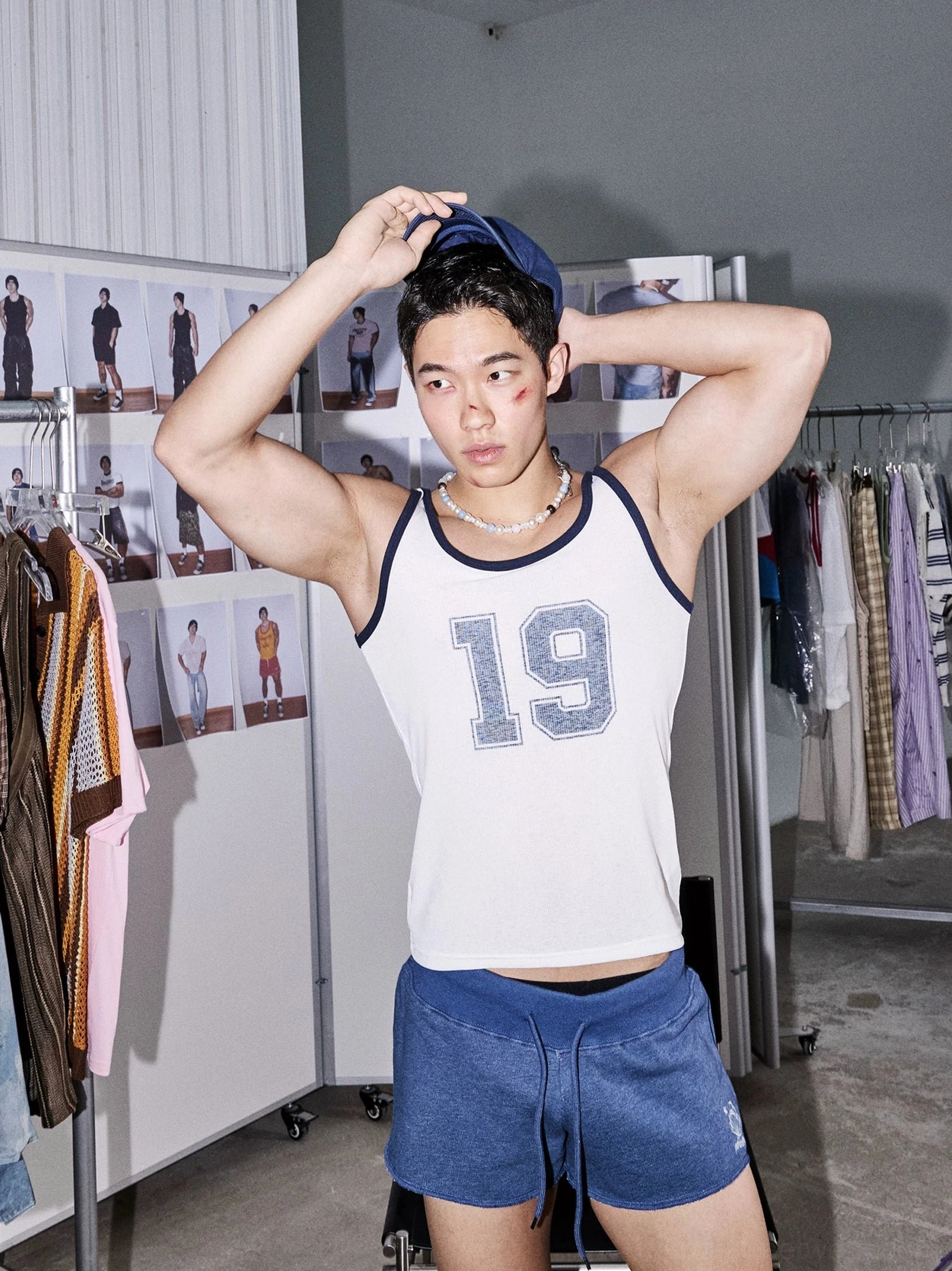 Close front view of indigo lounge sweat shorts styled with a white number graphic tank top in a modern streetwear showroom