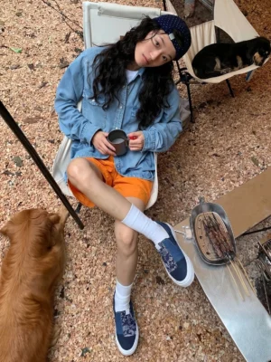 Blue paisley patchwork slip-on sneakers worn with white crew socks in an outdoor camping streetwear outfit beside a golden retriever