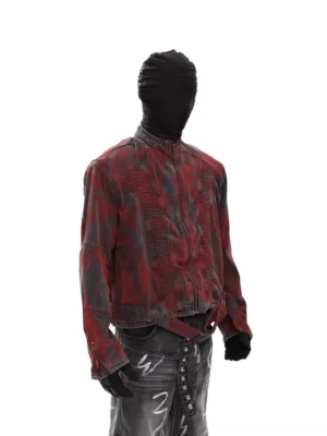 Left side view of red black washed biker denim jacket showing vertical accordion ruched panels, fitted cropped silhouette, and sculpted sleeves