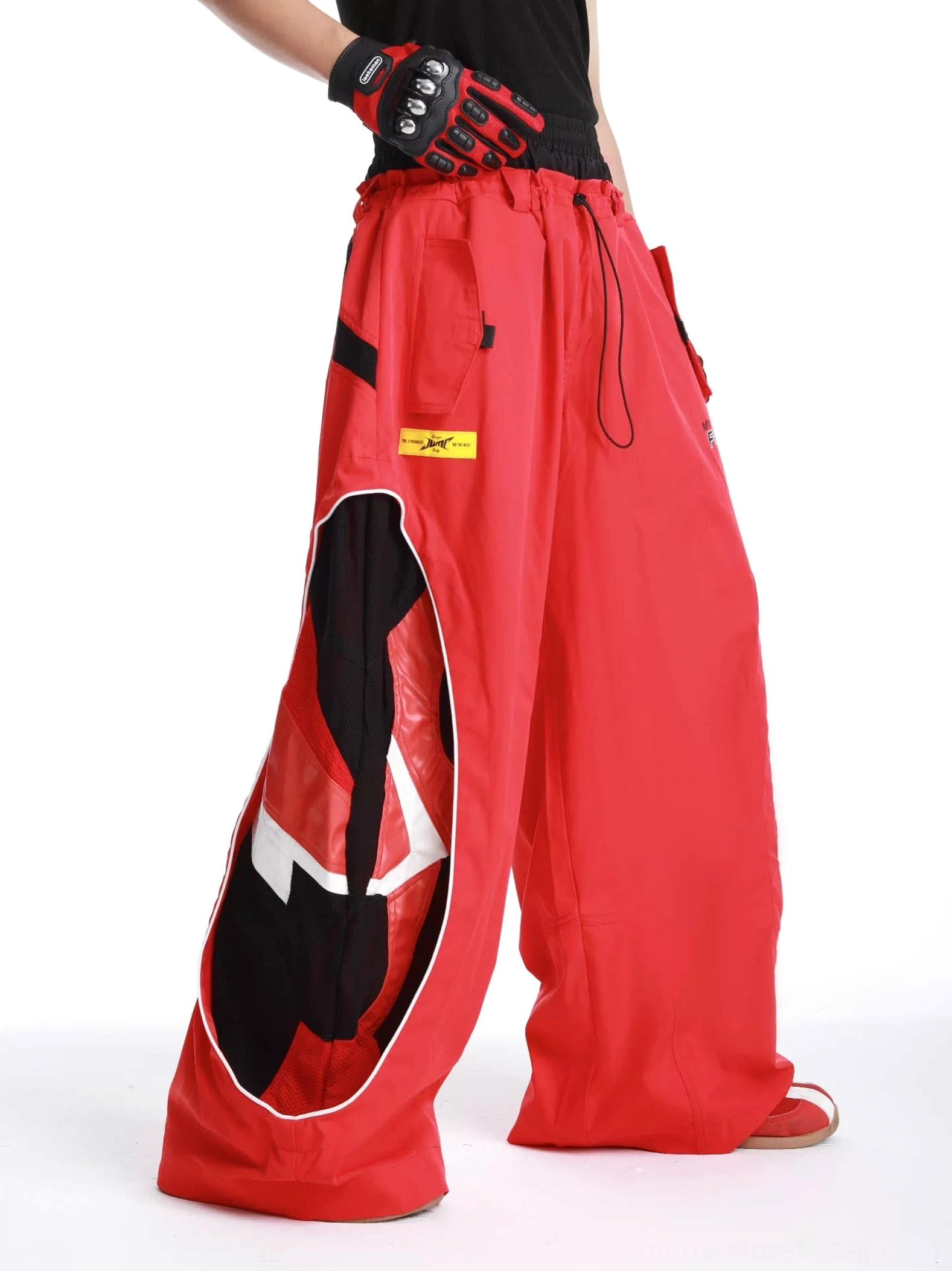 Red inferno vector wide-leg track pants side view showing curved black graphic racing-inspired panel